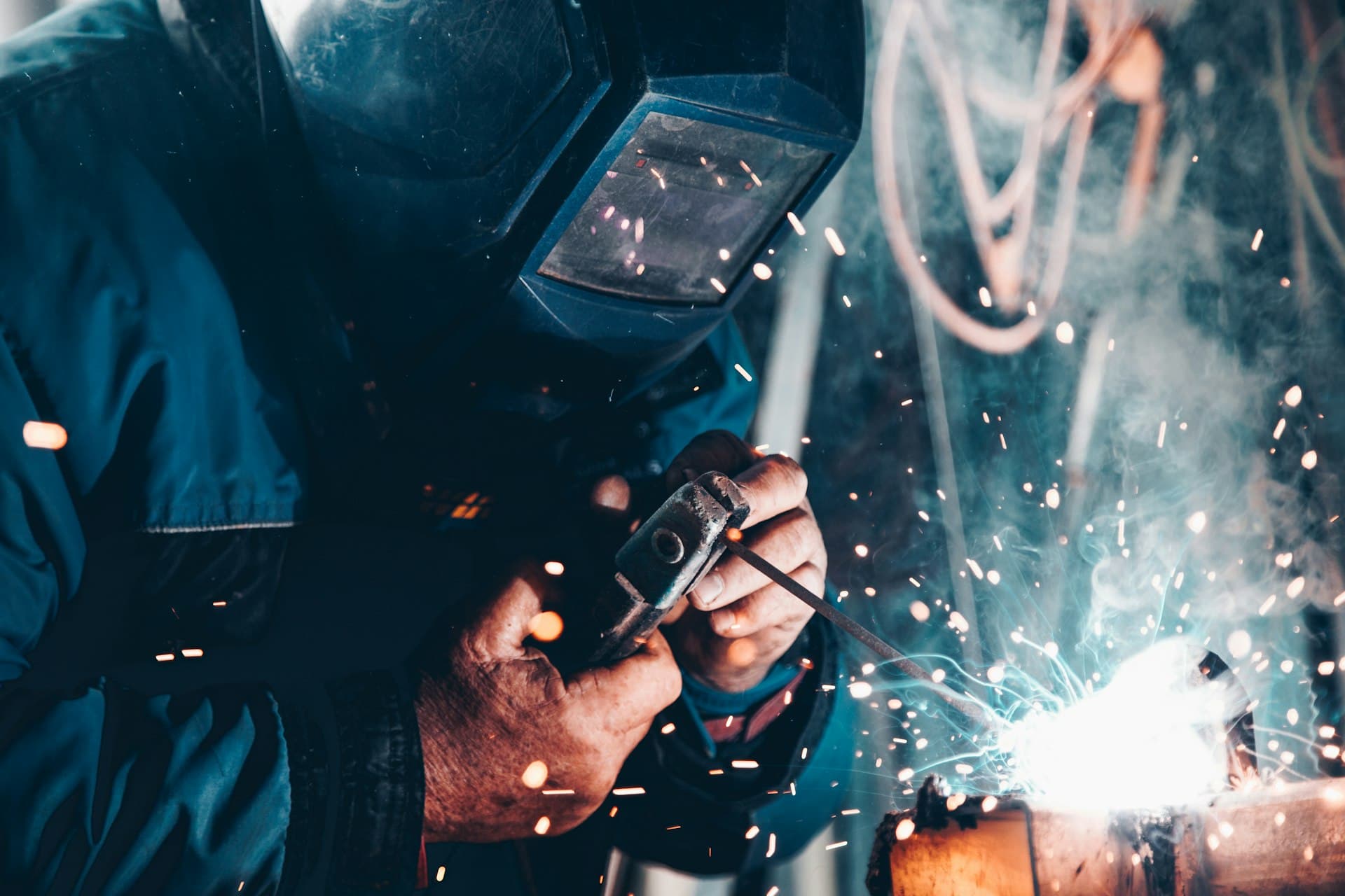Welder in protective clothing striking an arc with a shower of sparks