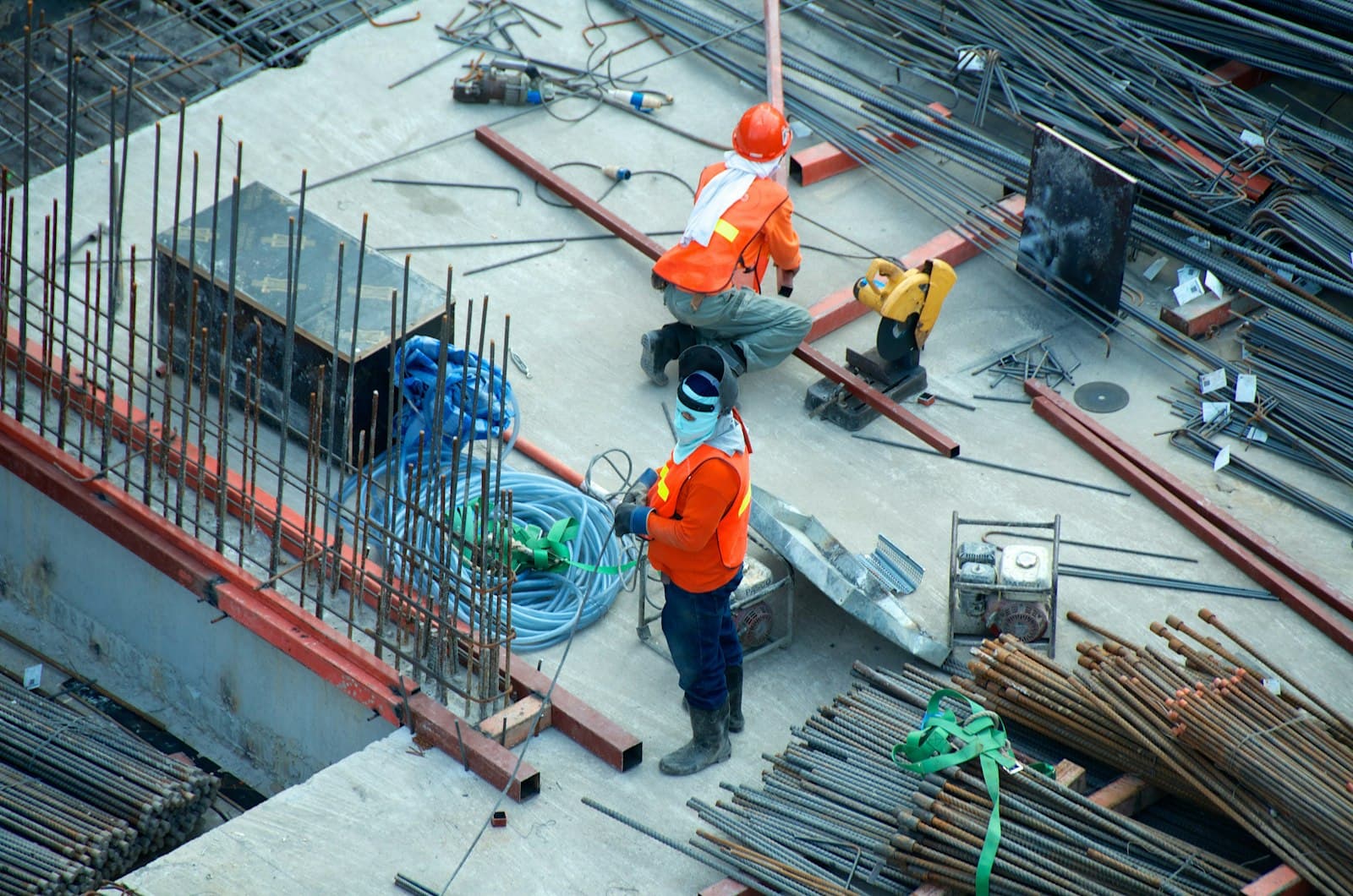 Site workers in high-visibility PPE with a welding helmet and metal saw