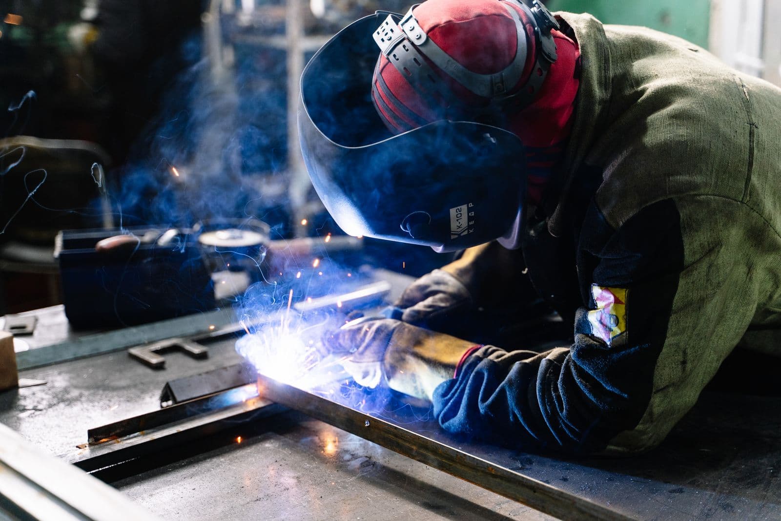 Welder in a helmet joining steel with a bright welding arc